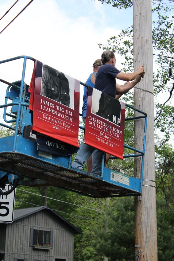 Morgan McGill, left and Todd Anderson, right, prep the utility pole to hang the banner